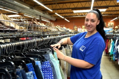 A worker at Goodwill Industries of San Diego County – a San Diego Workforce Partnership partner and subject of a Reimagine Retail publication – sorts clothing.