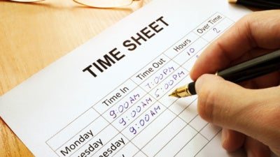 Employee writes hours on a time sheet