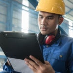 Photo of a manufacturing worker writing on a clipboard