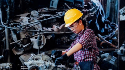Young Asian Engineer woman working with machine in factory.
