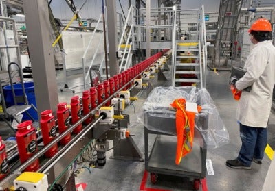 A person works with robots at Procter & Gamble’s Tabler Station factory in Martinsburg, W.Va., on May 28. (Timothy Aeppel/Reuters)