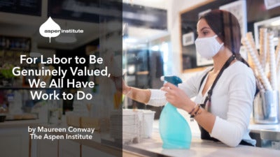 Promotional image for the blog post "For Labor to Be Genuinely Valued, We All Have Work to Do" by Maureen Conway, The Aspen Institute. The image includes the title of the piece. In the background is a photo of a young woman with a face mask working in a cafe, wiping down a plastic barrier.