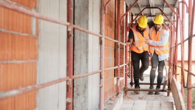 Injured construction worker being helped by colleague