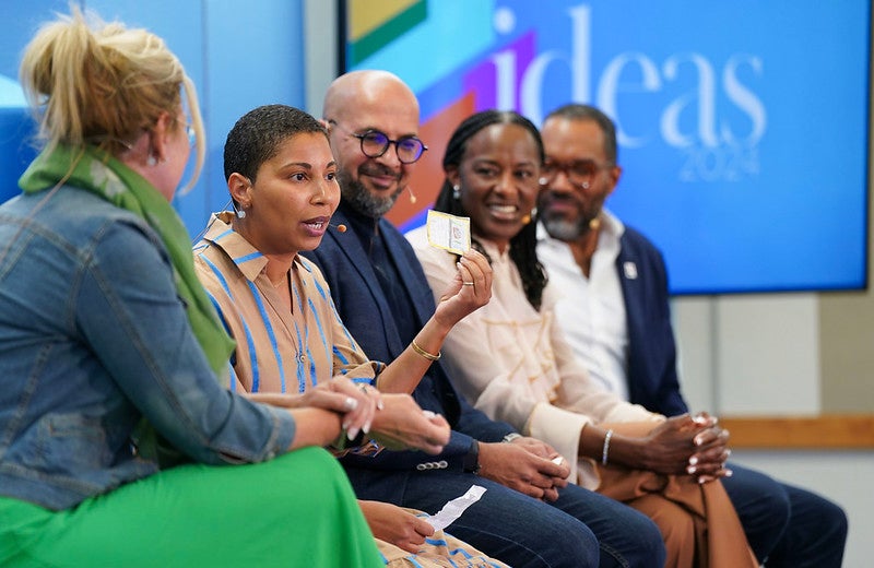 5 panelists look as one holds up a dollar bill.