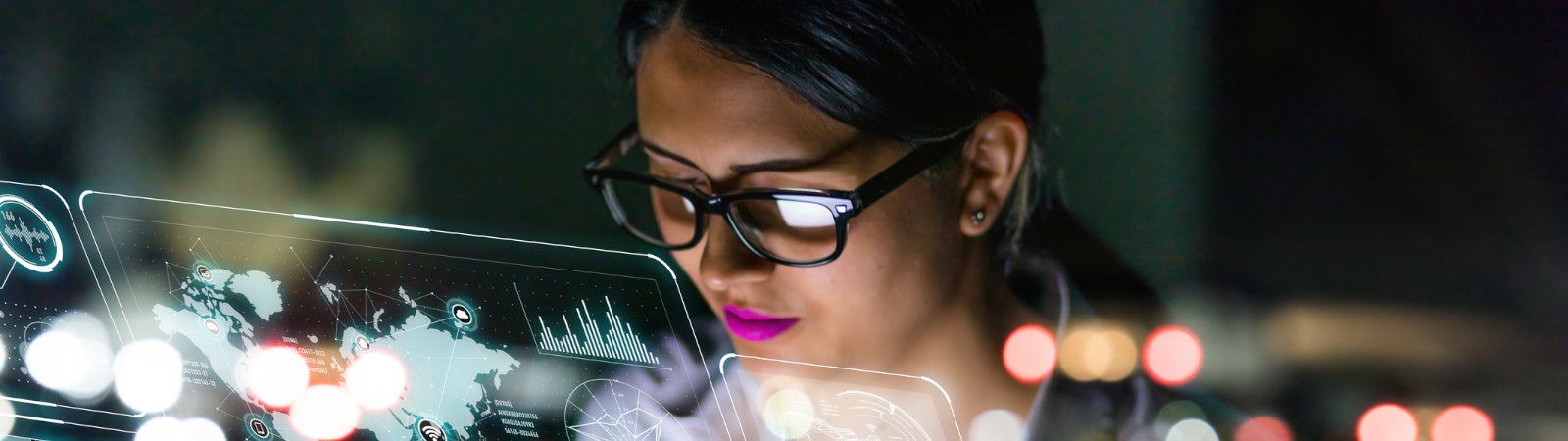 Photo of a Latin woman in glasses looking at charts on a futuristic screen.