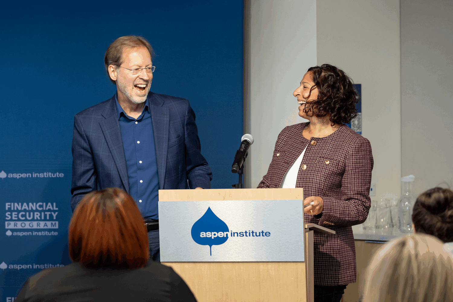Aspen Institute's Dan Portfield and Joanna Smith-Ramani laugh at a podium during a public event.