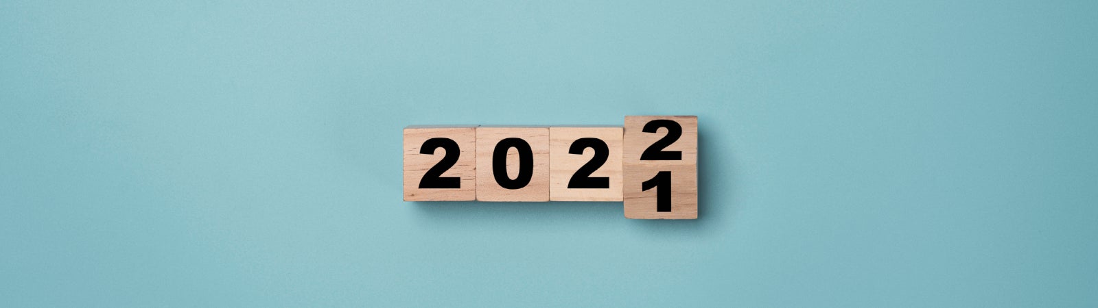 Photo of wooden blocks spelling out the year. The final block is in the process of flipping from 2021 to 2022.