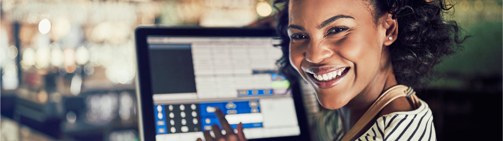 Photo of a smiling Black woman using a touchscreen cash register