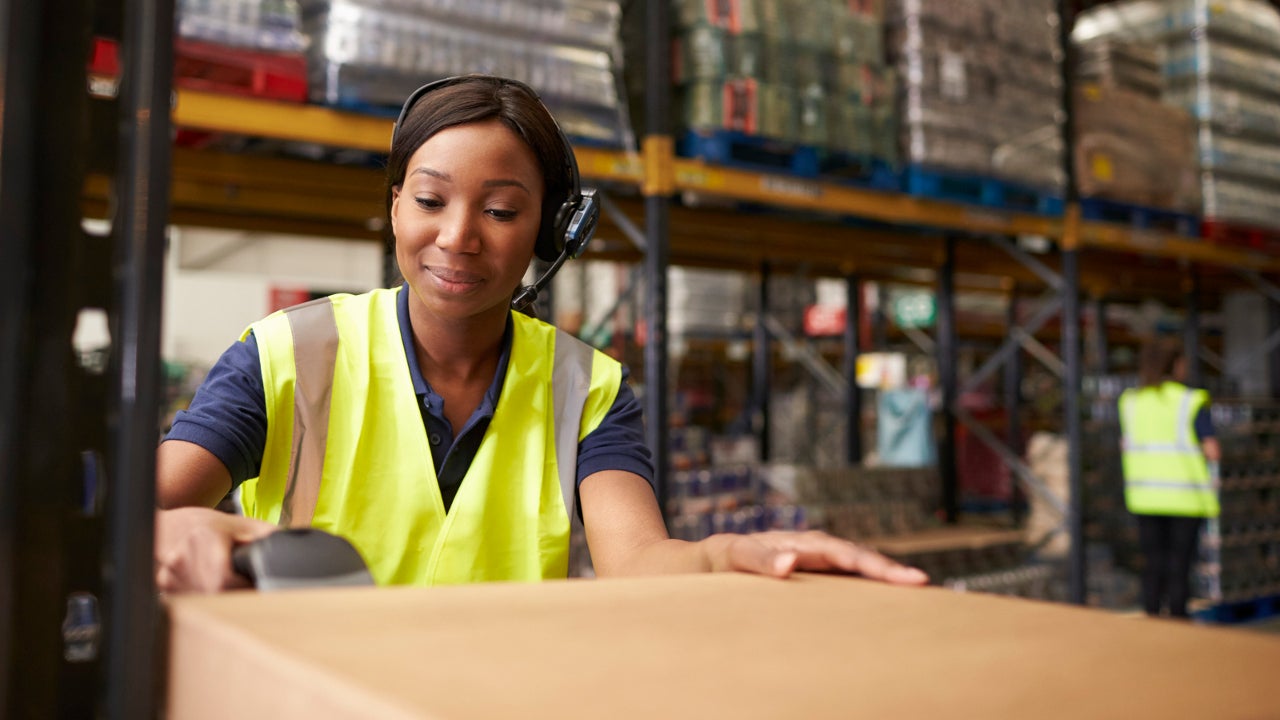 African American woman scanning boxes in a warehouse