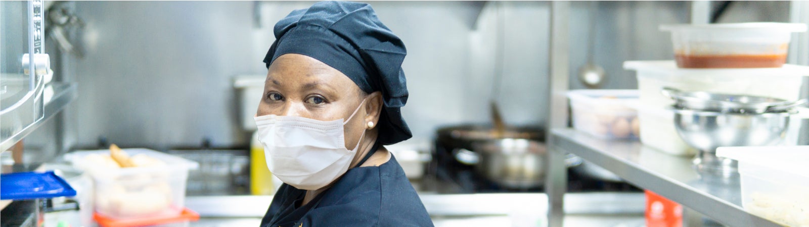 African American woman restaurant worker wearing a face mask in the kitchen