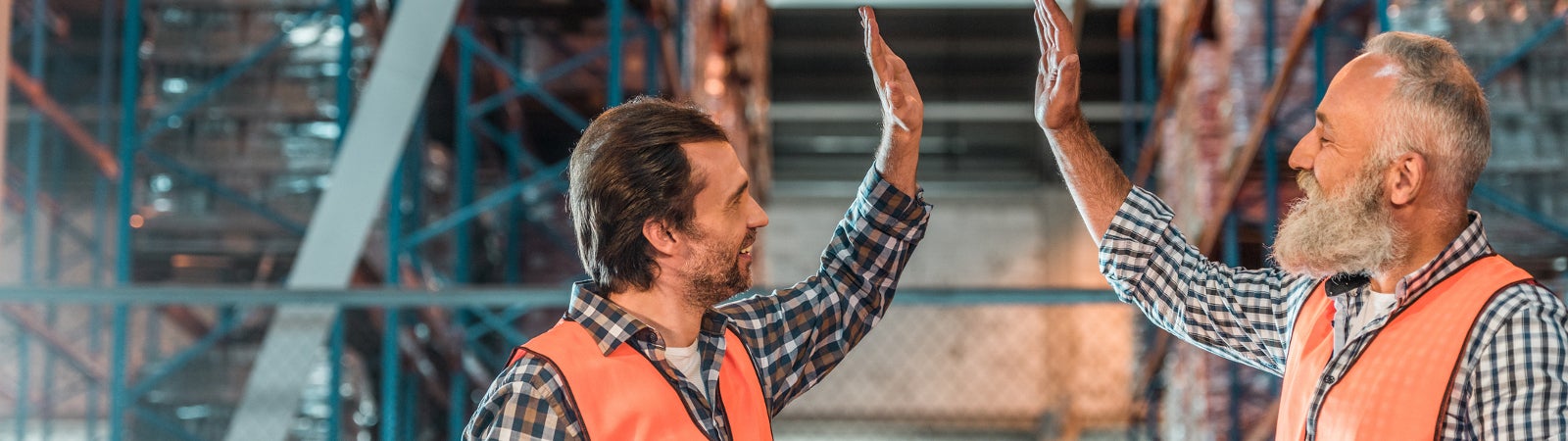 Two male warehouse workers share a high five