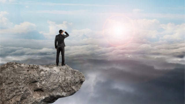 Man standing on a mountain, staring toward another mountain