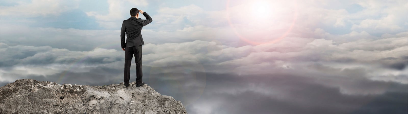 Man standing on a mountain, staring toward another mountain
