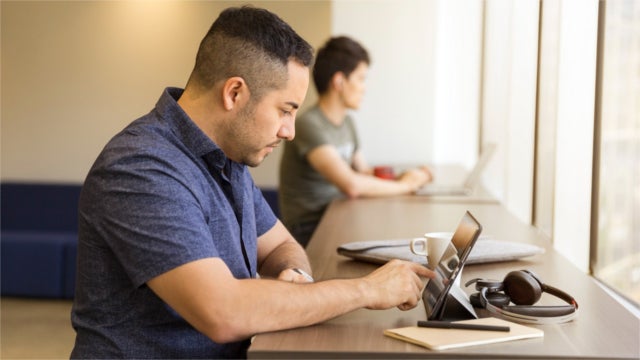 Man Sitting on White Chair Pointing on Tablet Screen Inside Room