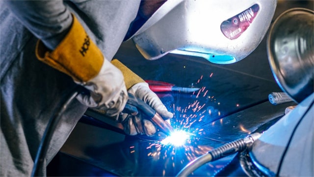 Auto worker welding a car