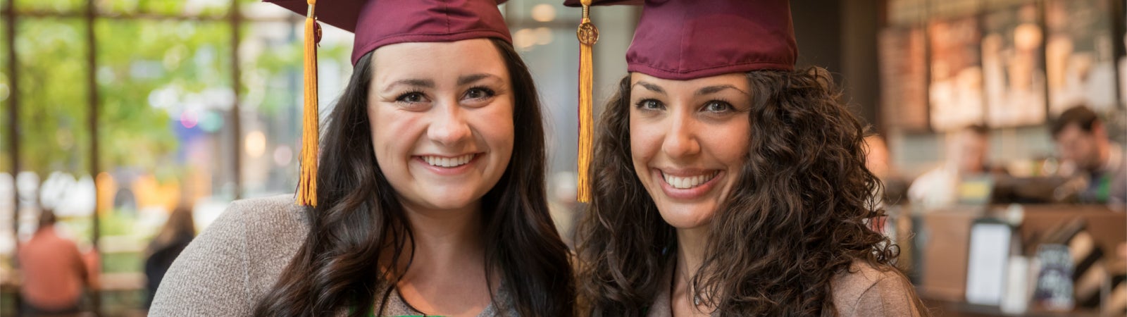 Two Starbucks employees celebrate their graduation from the Starbucks College Achievement Plan