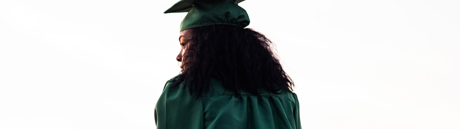 Woman in graduation cap and gown staring into the distance