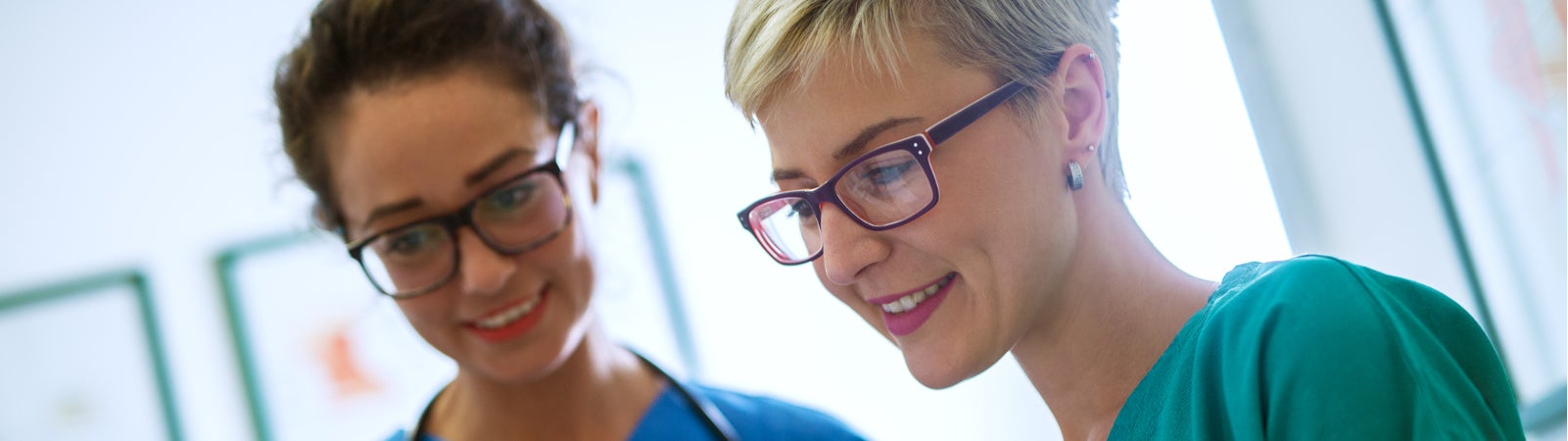 Close up view of two professional nurses with eyeglasses checking the patient papers in a doctors office.