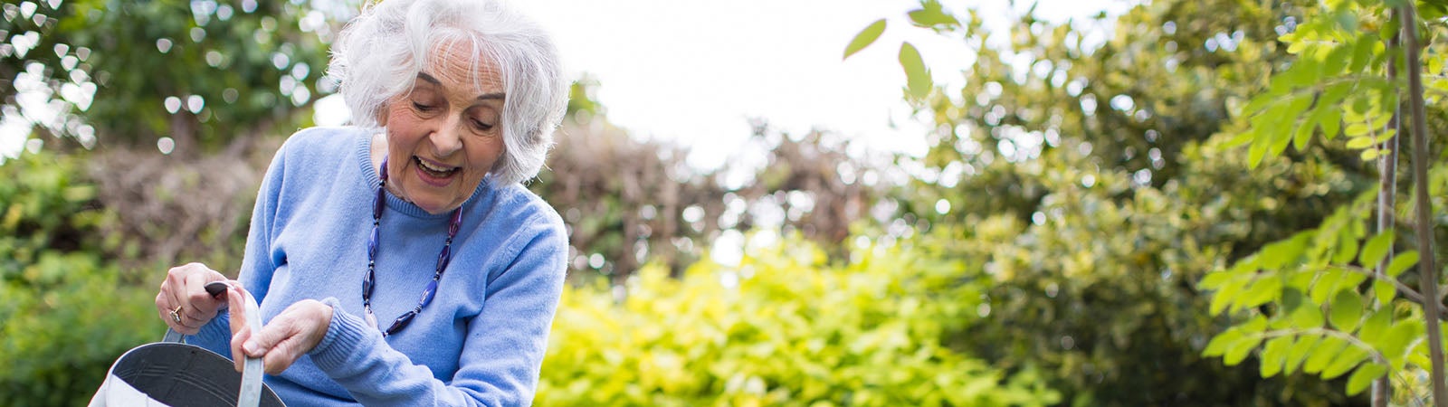 Senior Woman Watering Flowers In Garden