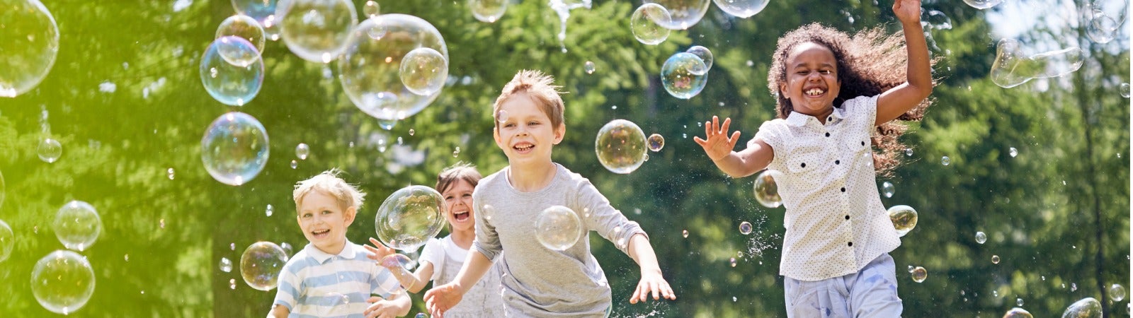 Children chasing bubbles in a park.