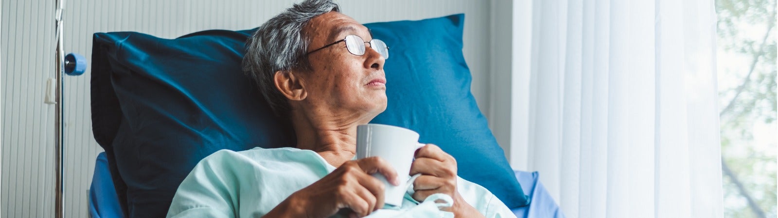 A man sits in a hospital bed looking out the window.